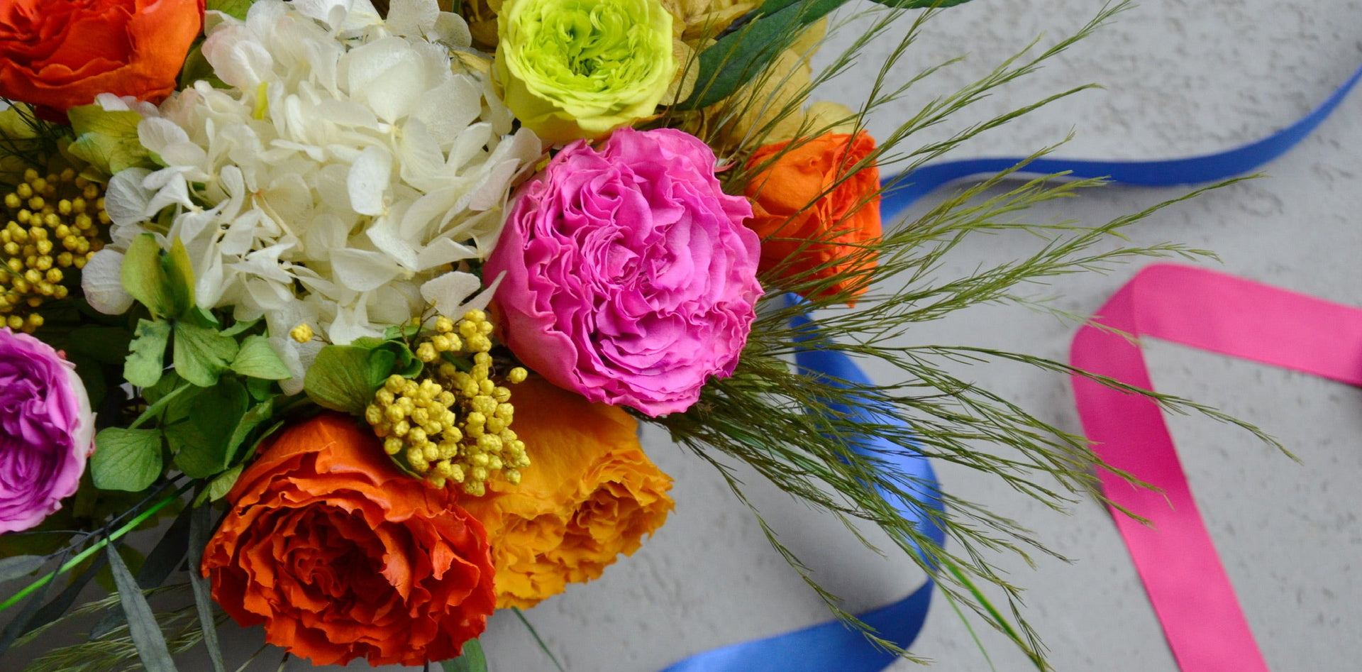 Colorful bouquet of flowers with ribbons on a light background